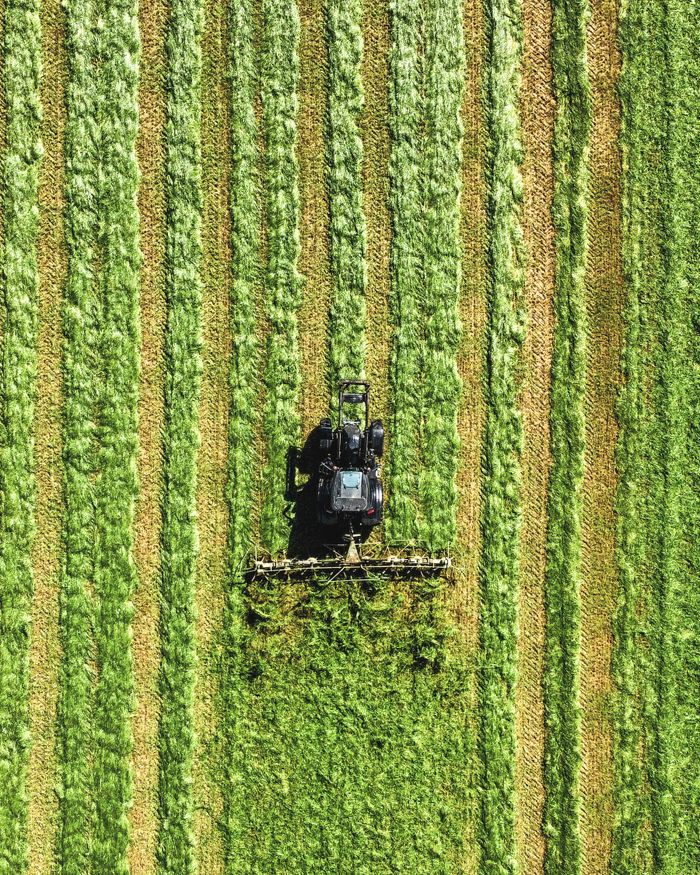 Mastering the First Impression: Your intriguing post title goes here Aerial shot of a tractor harvesting green crops in a striped pattern field.